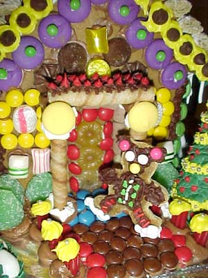 Another new feature this year is my porch. It's a little hard to tell in the picture, but the columns are about half an inch out from the wall. Julie decorated the top of the porch with red and brown icing. A gingerbread man sits in front.